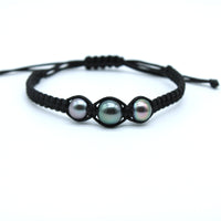 A black macrame bracelet featuring three small iridescent pearls, displayed on a clean white background.