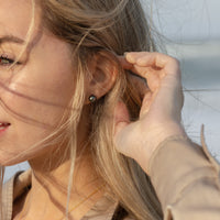 Model wearing a pair of Tahitian Black Pearl stud earrings and a matching floating pearl necklace