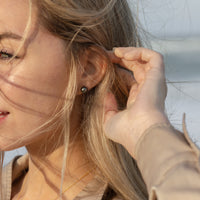 Model wearing a pair of Tahitian Black Pearl stud earrings and a matching floating pearl necklace