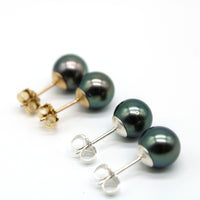 Pair of pearl earrings with gold and silver posts on a white background