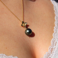 Model wearing a large gold flower pendant with Tahitian black pearl