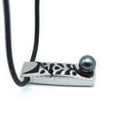 Necklace with a rectangular pendant featuring a black and silver pattern and a green pearl on a white background