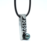 Necklace with a silver pendant featuring a black design and a black pearl on a white background