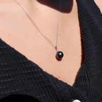 Model wearing a white gold necklace featuring a black pearl pendant