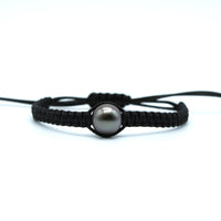 Black macrame bracelet with a black pearl on a white background