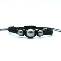 Black macrame bracelet with three pearls on a white background