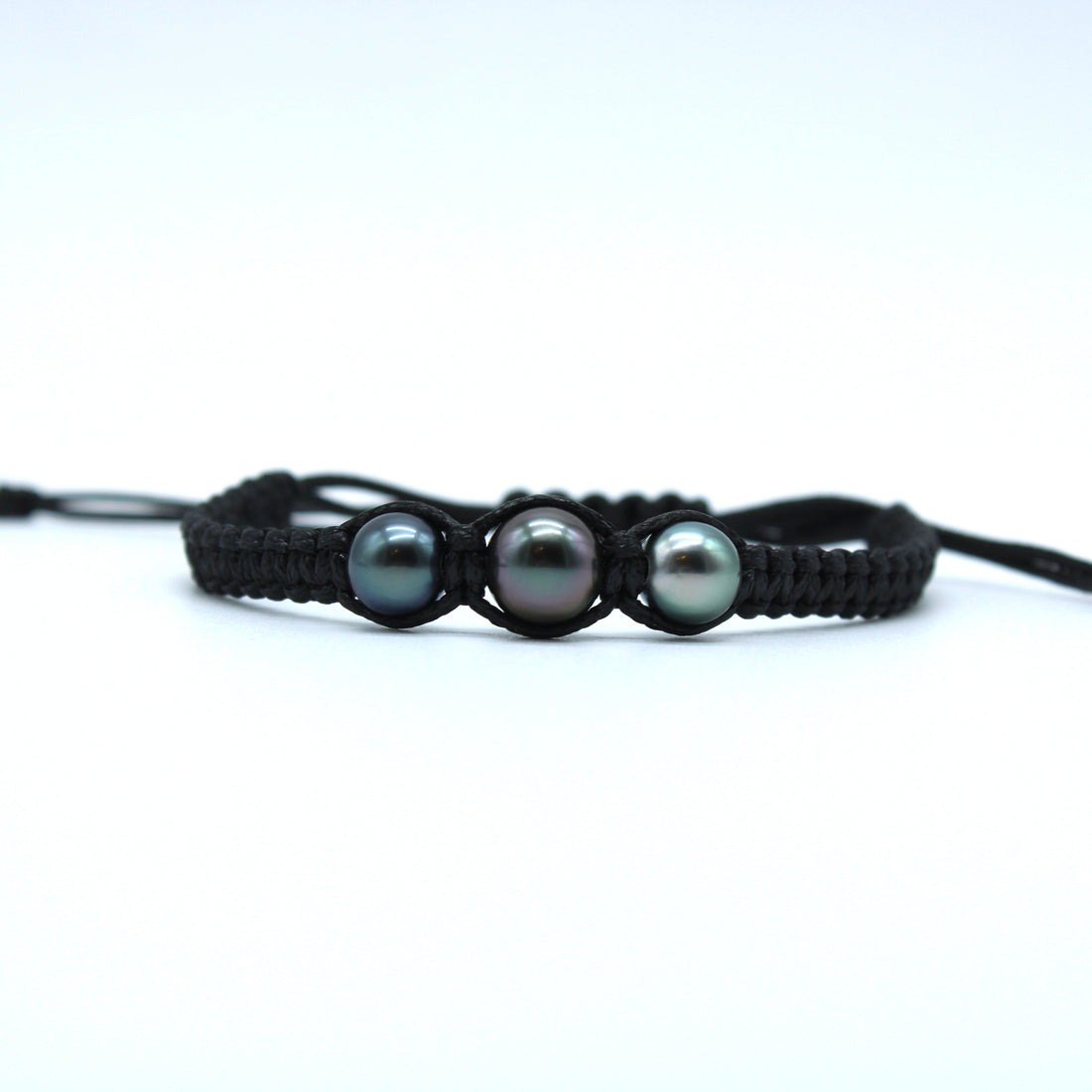 Black braided bracelet with three gray pearls on a white background
