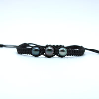 Black braided bracelet with three gray pearls on a white background