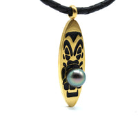 Gold pendant with black design and a black pearl on a white background