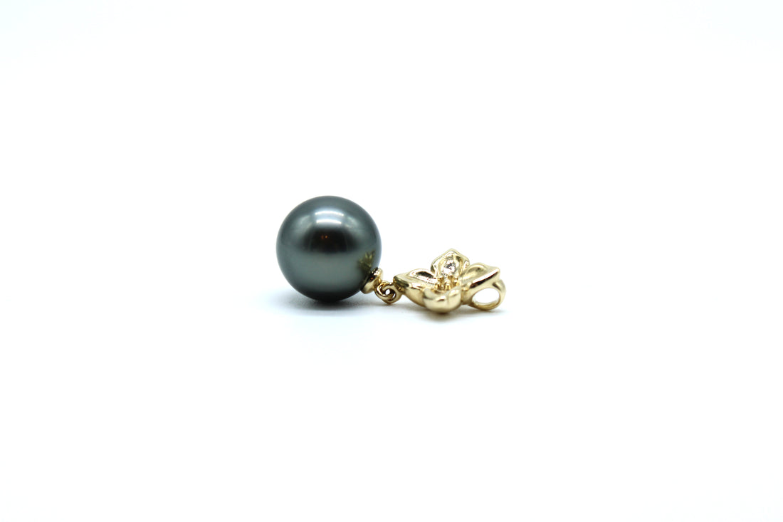 Side view of large gold flower pendant with a Tahitian black pearl with a white background