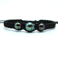 Black braided bracelet with three pearls on a white background