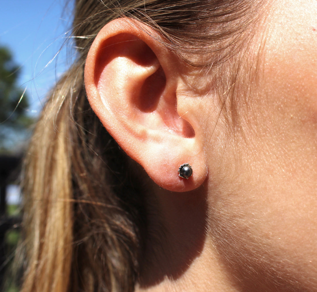 Model wearing small shell earrings featuring a keshi pearl 