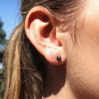 Model wearing small shell earrings featuring a keshi pearl 