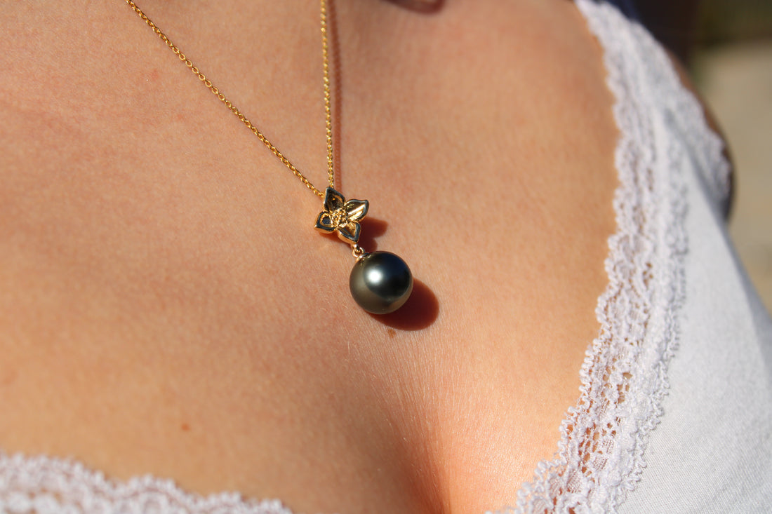 Model wearing a large gold flower pendant with Tahitian black pearl 