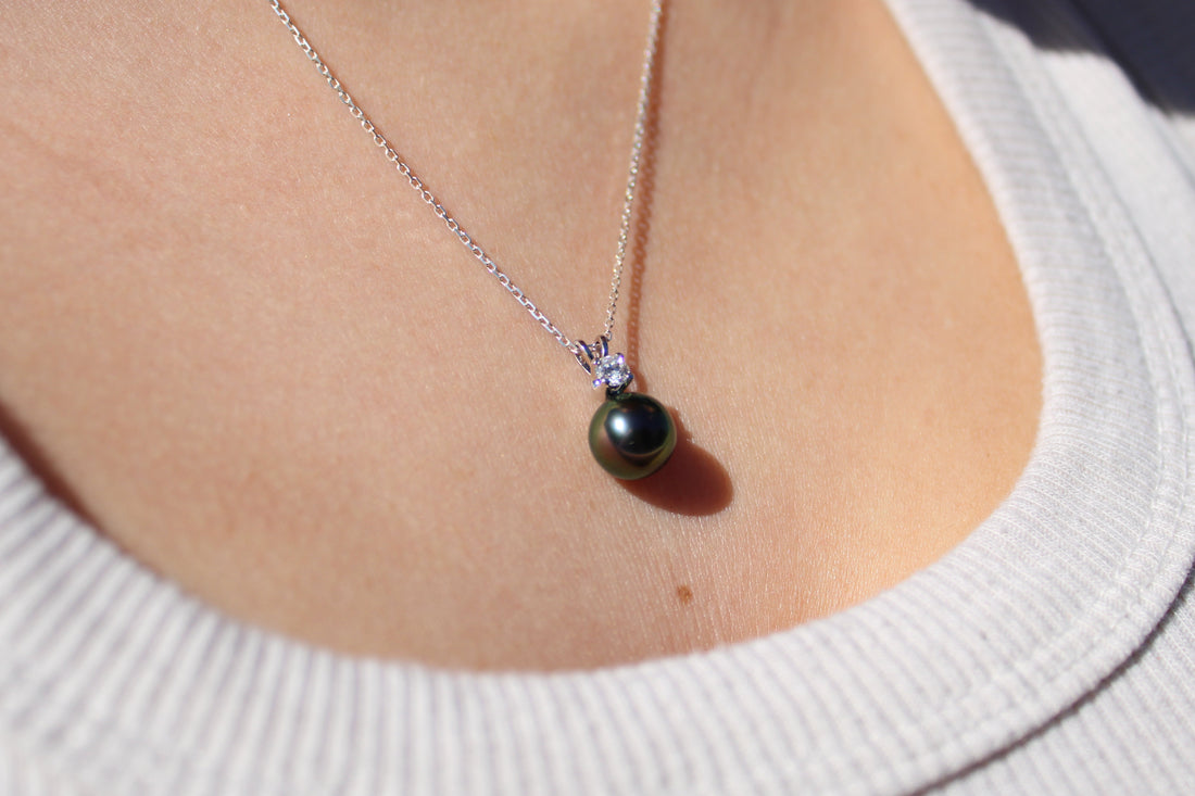 Model wearing a white gold and lab grown diamond pendant featuring a black pearl 