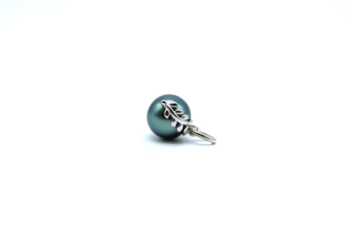 Sterling silver blue tahitian pearl pendant with a leaf design laying on the side with a white background