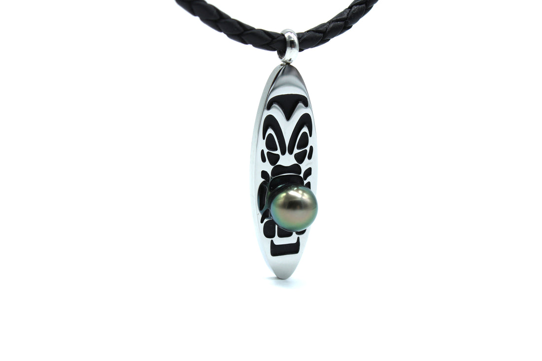 Necklace with a sterling silver surfboard medallion featuring a tahitian black pearl on a white background