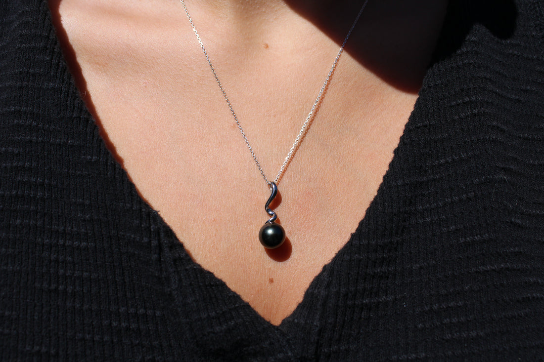 Model wearing a sterling silver necklace featuring a swirl shaped pendant with  black pearl 