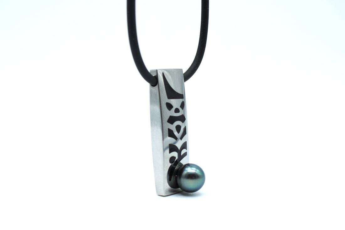 Necklace with a silver pendant featuring a black design and a black pearl on a white background