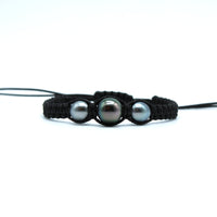 Black braided bracelet with three Tahitian black pearls on a white background