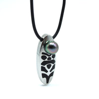 Necklace with a tiki pendant featuring a black pearl on a white background