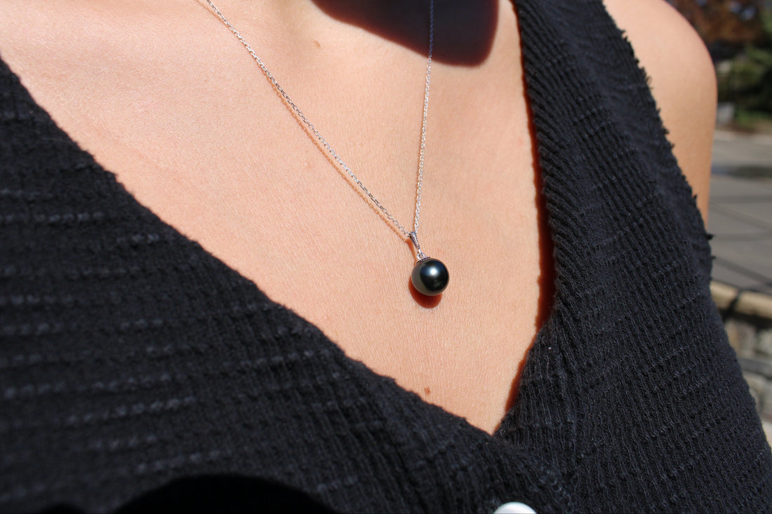 Model wearing a white gold necklace featuring a black pearl pendant